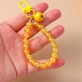 Close-up of handmade yellow beaded keychain featuring a metal clasp and matching yellow bell - Yellow