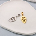 Detailed view of silver and gold skull charms with lobster clasps on a white tray - Skull Style 1