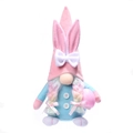 Gnomo de Pascua de peluche con orejas de conejo rosas y un huevo moteado en sus manos - Estilo de Mujer