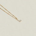 Minimalist golden necklace featuring a pearl-inlaid letter L pendant on a white surface - Letter L