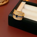 Detailed close-up of wide gold-plated ring with emerald cut blue stone and pavé zircons - Gold-Blue Zirconia