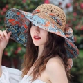 Close-up of straw sun hat featuring vibrant orange and blue paisley print ribbon and bow - Totem Floral Khaki