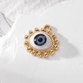 Blue evil eye charm with gold trim and crystal accents on a white stone background - Grey Bead Eye