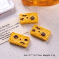 Makro-Detail des Miniatur-Resin-Cranberry-Keks-Anhängers mit gelber Textur - Gelb