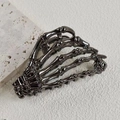 Detail view of a dark gunmetal skeleton hand hair claw clip on a textured stone surface - Alloy Metal / Gun Black Skeleton Hand (8.5cm)