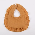 Detail of ginger cotton muslin baby bib with ruffled lace edges and snap button fastener - Orange