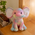 Rainbow tie-dye plush elephant toy sitting on a wooden table in a cozy home setting - Colorful White Ear Core/Tie-Dye