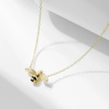 Detailed close-up of a gold bee pendant with sparkling white zircons and black enamel - 925 Silver / Gold