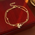 Dettaglio del bracciale dorato a doppio strato con ciondolo a fiore in zirconi e catena snake - Oro