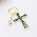 Macro detail of golden cross keychain set with green rhinestones and a clear water drop - Green-2