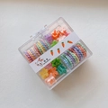 Detalle macro de pinzas para el cabello y gomas en espiral para niños en caja transparente - Flor