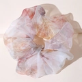 Macro shot of oversized organza scrunchie featuring delicate floral prints in light pink and orange - Dreamy Floral