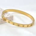Detailed macro view of 18k gold plated stainless steel heart bangle with crystal studs - Heart / Gold