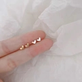 Minimalist 925 silver heart stud earrings in gold and silver finish shown on a finger - Small Heart / Silver