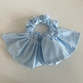 Dettaglio di uno scrunchie in raso azzurro con ampie ruches pieghettate e cuciture curate - Blu