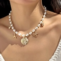 Close-up of pearl necklace with gold starfish and seashell pendants on female model neck - Pearl Shell Starfish