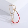 Detailed view of a gold and red stethoscope brooch on a white geometric display stand - Gold Base Red