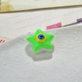 Macro detail of a green star-shaped resin bead with evil eye design for DIY jewelry making - Green