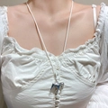Dettaglio del ciondolo a forma di pony argento su cordino bianco con top a balze - Pony Argento Lucido (6300)
