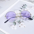 Close-up of retro round purple sunglasses with gold metal frames on a magazine - Silver Frame Purple Lens