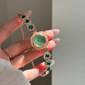 Detail of rose gold watch bracelet featuring emerald green gems and zircon bezel - Gold-Green
