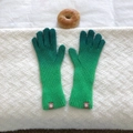 Detail of gradient green knit gloves with extended ribbed cuffs on white textile surface - Emerald Green