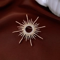 Macro detail of vintage gold plated sunburst brooch with pavé zircon on silk fabric - Gold