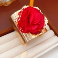 Detalle de brazalete dorado texturizado con una gran flor roja de tela en estuche de joyas - Brazalete ancho dorado con flor roja