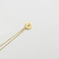 Minimalist gold necklace with a circular pendant featuring a diamond-set letter X - Letter X