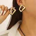 Boucles d'oreilles géométriques dorées et noires présentées sur un mannequin - 05 Boucles d'Oreilles Clous Triangulaires Géométriques en Or Mat (2000)