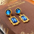 Vista macro di orecchini vintage dorati con cristalli blu su un libro d'epoca - 27# Silver Earring Post - Blu Quadrato