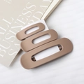 Three matte beige and brown rectangular hollow hair clips stacked on a book - Light Coffee