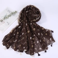 Detail of dark brown paisley linen scarf with fringes and eucalyptus leaves on a white surface - Style 9