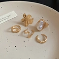 Set of five gold flower rings with pearls displayed on a minimalist ceramic plate - Gold Pearl 5-Piece Set