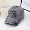 Detail der grauen verwaschenen Baseballkappe mit M-Stickerei und Stern-Ausschnitt am Schirm - Grau