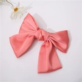 Detail view of pink satin bow hair clip with long ribbons on white background - Watermelon red