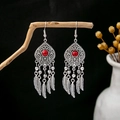 Detailed close-up of Bohemian silver hollow earrings with red beads and feather pendants - E2529-2 Red Feather Dangle