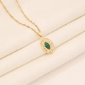 Dettaglio di una collana vintage dorata con pietra verde ovale e ciondolo traforato - Malachite