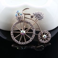 Golden bicycle brooch with sparkling clear crystals and iridescent accents on black surface - Xd825386