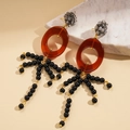 Macro shot of resin oval hoop earrings with black beaded tassels and grey crystal studs - Coffee (Silver Earring Post)