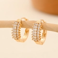Detail of gold-plated hoop earrings with micro-paved cubic zirconia on a wooden branch - EH231 Three Row Warm Gold