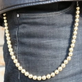 Close-up of a stylish gold metal ball chain accessory hanging on dark blue denim jeans - Gold Round Bead Style