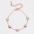 Detalle de pulsera de acero inoxidable en oro rosa con cinco colgantes de corazón sólido - Oro rosa