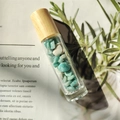Essential oil roller bottle with wooden cap and green crystal stones inside - Amazonite