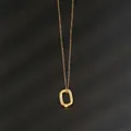 Close-up of polished gold oval pendant on a delicate chain over black texture background - Rectangle