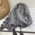 Gray voile headscarf with handmade tassel beads shown with a straw bag on a white table - Dark Gray
