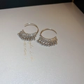 Macro shot of silver C-shaped metal earrings with textured finish and drop tassel charms - Hook Style / Silver