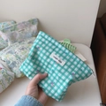 Close-up of small green plaid cosmetic bag with floral print and zipper closure - Dark Green Grid Floral