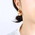Golden and white enamel C-shaped chunky hoop earrings worn by a female model - Gold White Enamel Earrings