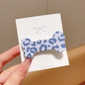 Close-up of blue leopard print bone-shaped hair clip on a white display card detail - Blue Leopard